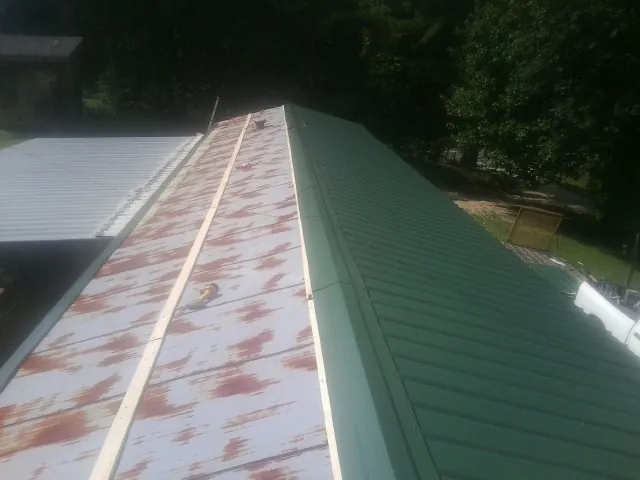 Old rusted panels beside newly installed green metal roofing — Wind Damage Roof Repair by Roofing Brothers in Horton