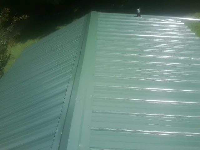 New green metal panels meeting at the ridge of a roof — Flat Roof Repair work by our crew in Horton
