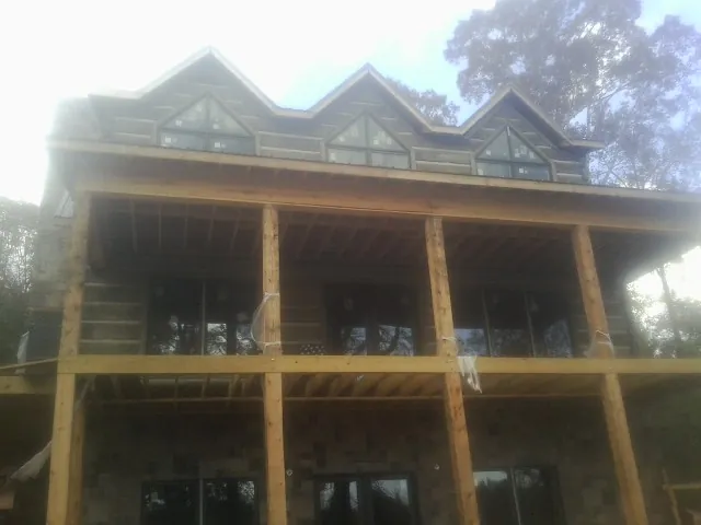 Dormers and porch framing on a large log home under construction — Roof Coating work by our crew in Horton