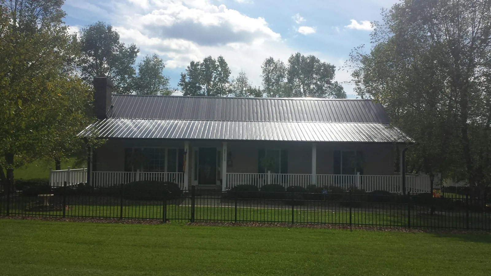 Gray metal roof on a brick ranch with a full width front porch — Gutter Guard Installation work by our crew in Horton