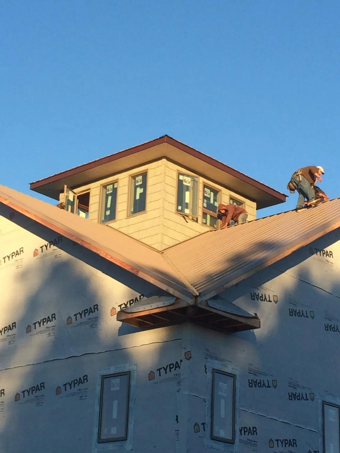 Roofers working around a rooftop cupola on a new metal roof at sunset — Roof Waterproofing in Horton by Roofing Brothers